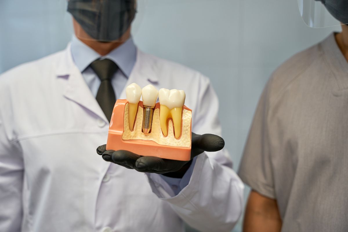 Dentist holding a dental implant model during a patient consultation