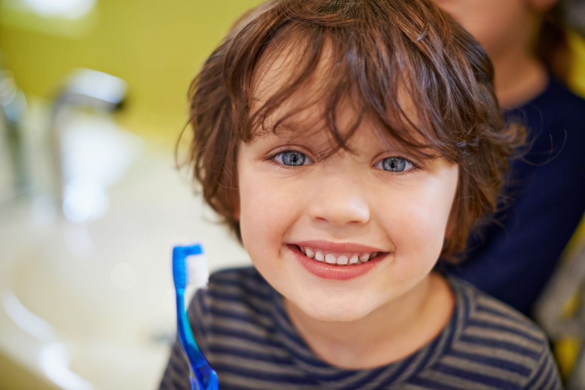 Happy child holding a toothbrush and showing a healthy smile